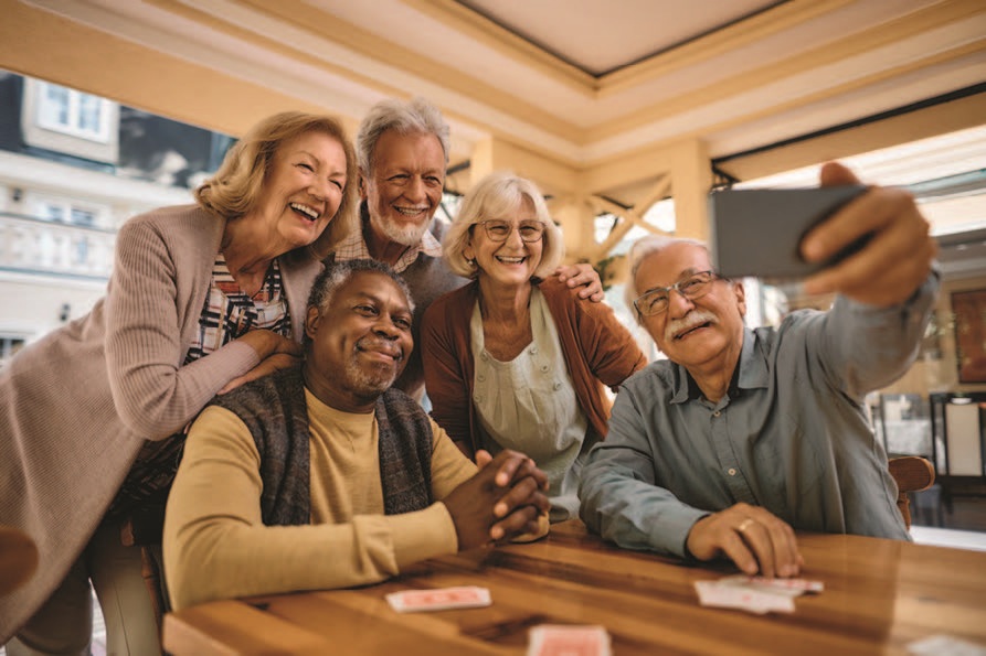 A group of seniors smile as they look at a phone camera.